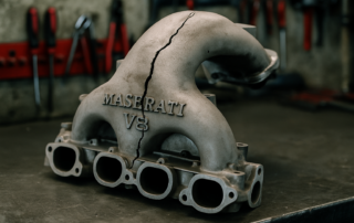 cracked intake manifold from a Maserati F136 V8 engine laid on a workbench