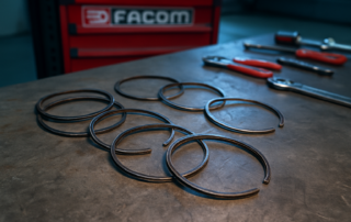 worn piston rings from a Nissan 370Z VQ37VHR engine laid out on a workbench