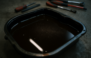 Audi A6 C7 DL501 S-Tronic gearbox oil drain pan with dark used transmission fluid and metallic particles visible